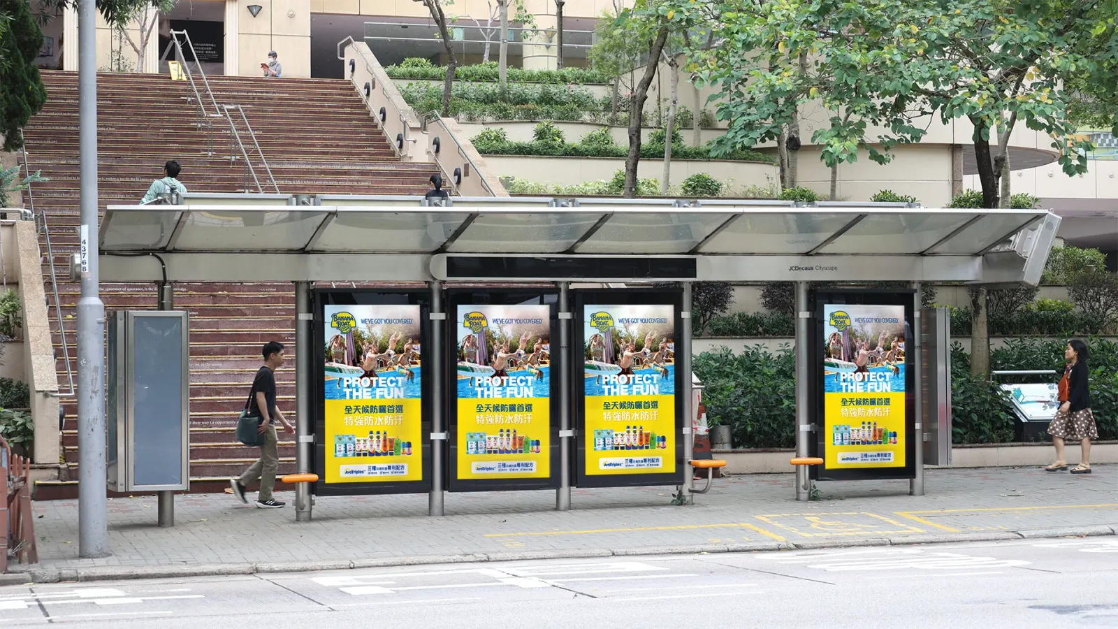 Four digital bus-shelter screens showing a yellow Banana Boat sunscreen ad headed “Protect the fun”